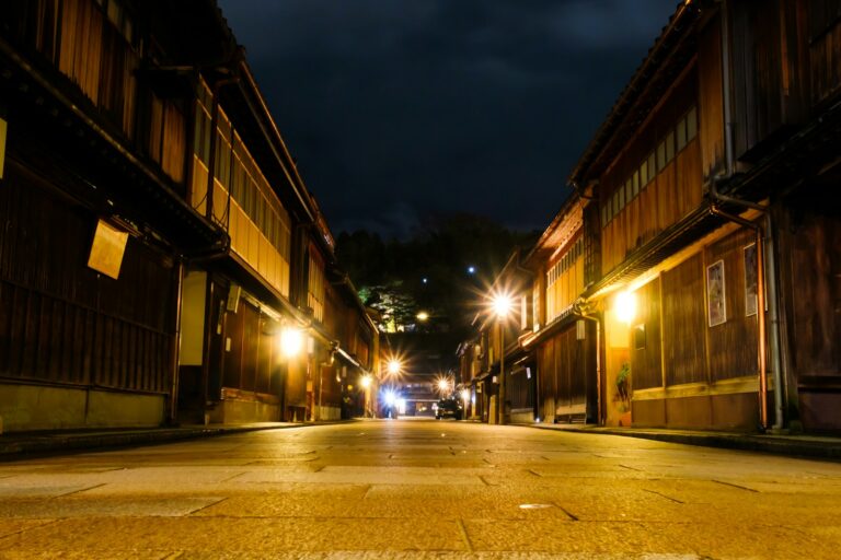 a street at night with a few cars parked on the side of the street