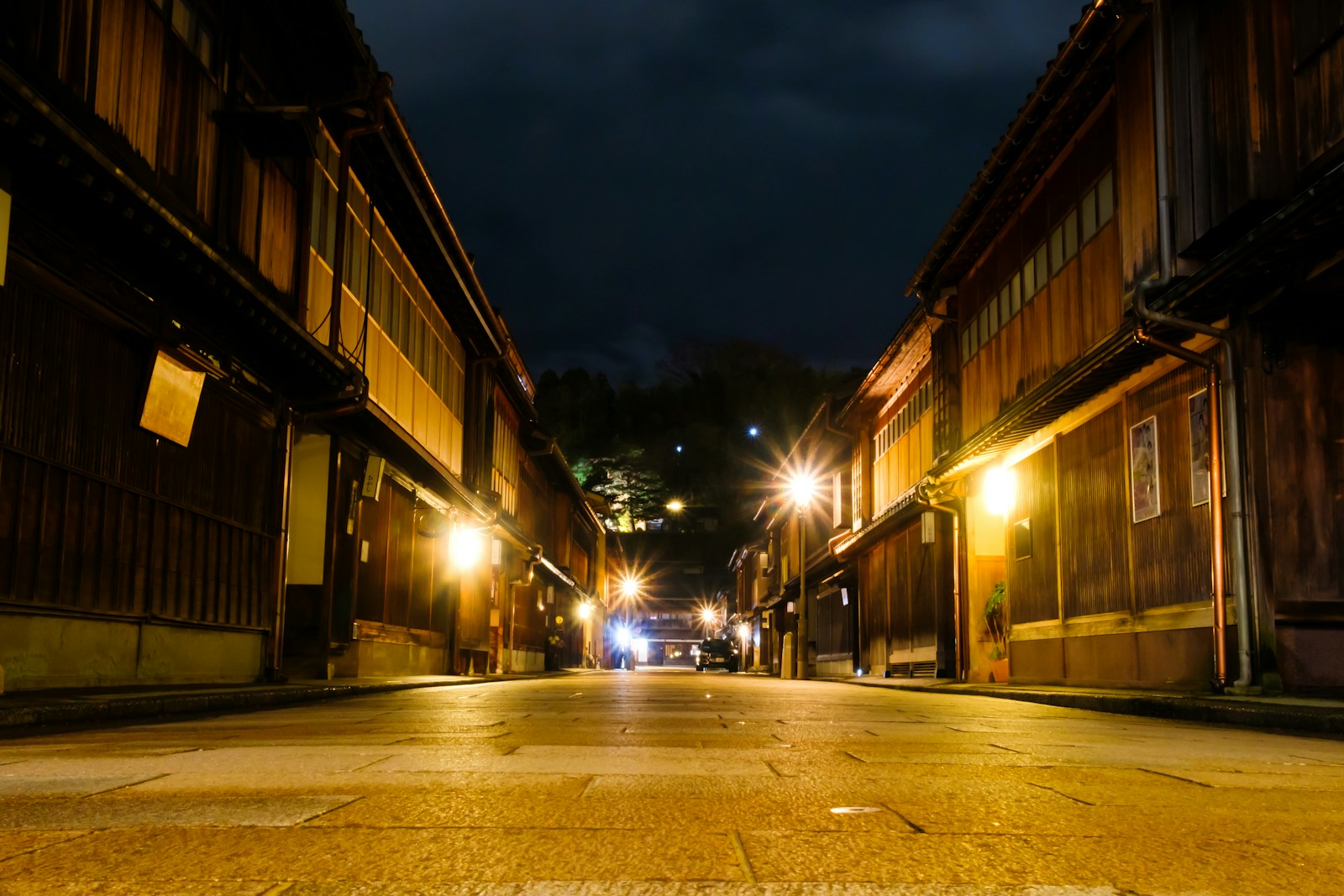 a street at night with a few cars parked on the side of the street